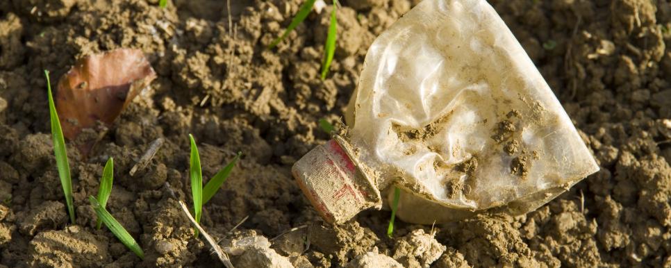 Zerdrückte schmutzige Plastikflasche auf Erdboden