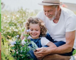 Mann hilft Kind bei Gartenarbeit